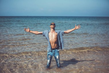 Genç kaslı adam poz veriyor ve elleri açık duruyor.