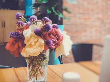 Kır çiçekleri ve kurumuş çiçekler bir bardaktaki suyun içinde bir yol kafeteryasındaki masada. Yakın çekim.