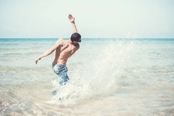 若い筋肉質の男が海の中でポーズをとって — ストック写真