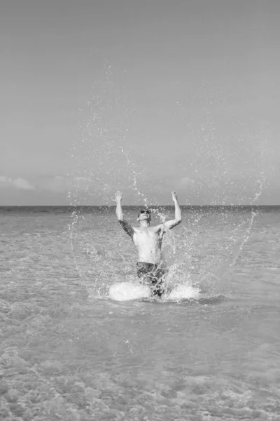 Joven musculoso posando y salpicando en el mar — Foto de Stock