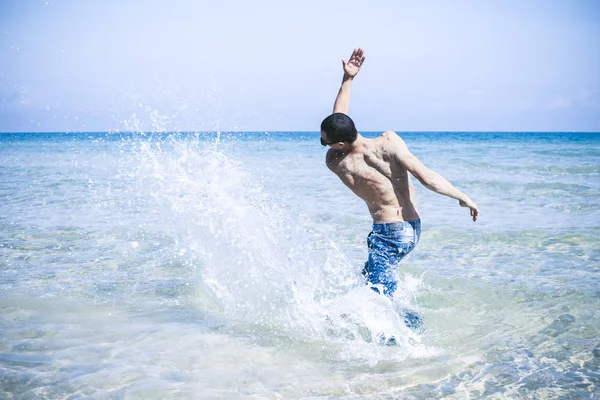Joven musculoso posando y salpicando en el mar —  Fotos de Stock