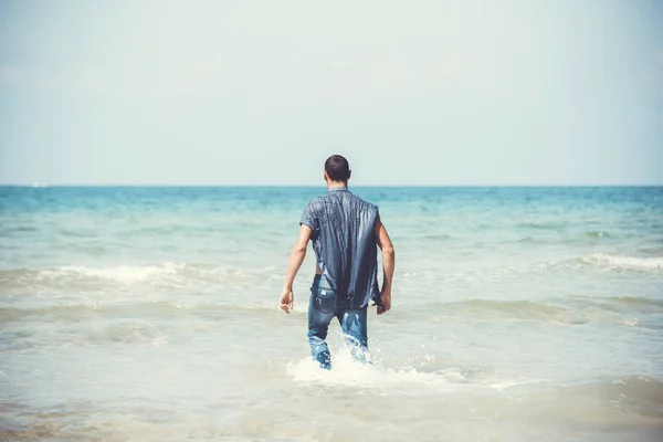 Giovane uomo muscoloso che riposa e posa sulla spiaggia. Un giovane uomo cammina in riva al mare — Foto Stock