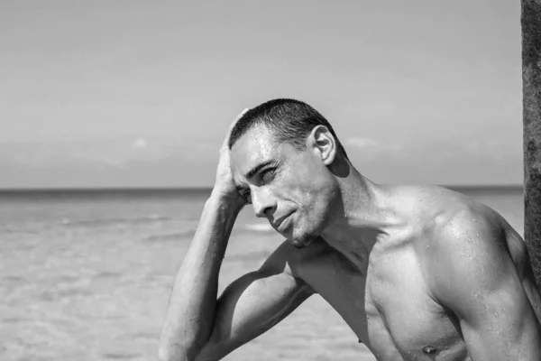 Jovem homem muscular descansando e posando na praia — Fotografia de Stock