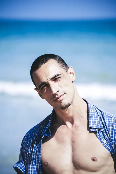 Jeune homme musclé se reposant et posant sur la plage — Photo