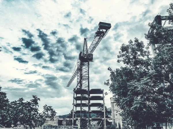Costruzione di un grattacielo. Gru costruzione trasporto merci. Cielo blu — Foto Stock