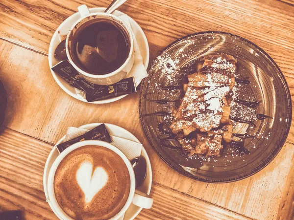 Lviv, Ucrania - 25 de diciembre de 2018: Copa blanca y platillo con un corazón de espuma de café y un postre delicioso. Vista desde arriba . —  Fotos de Stock