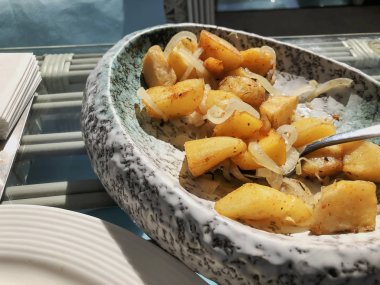 Tabakta kızarmış patates ve soğan.