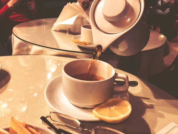Warme thee wordt van een theepot in een witte mok gegoten. Thee in het koude seizoen — Stockfoto