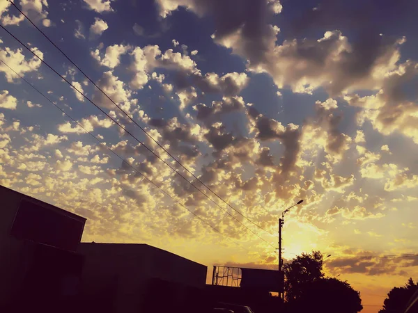 Céu nublado por sol com nuvens pitorescas iluminadas pela luz solar quente. Estrada rural ao pôr-do-sol — Fotografia de Stock