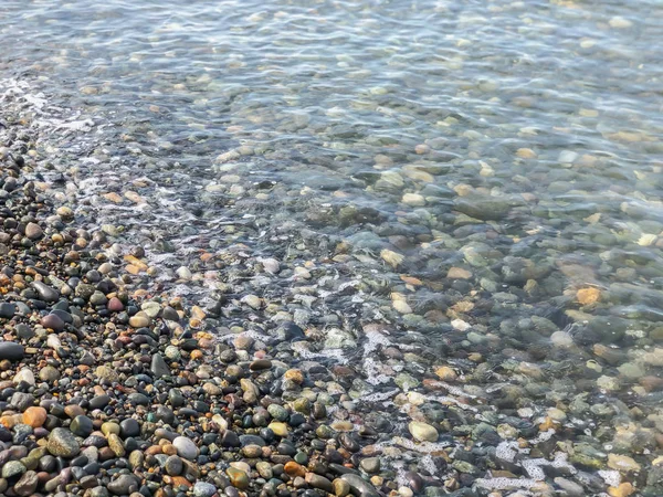 Vista de cerca de la hermosa playa de piedra del mar. Día soleado de verano, cielo azul, fondo de agua — Foto de Stock