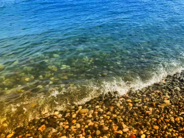 Vista de cerca de la hermosa playa de piedra del mar. Día soleado de verano, cielo azul, fondo de agua — Foto de Stock