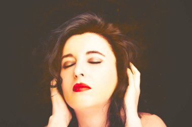 Uzun siyah saçlı, esmer, çekici bir kadın.