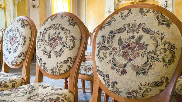 Una silla de madera con asientos y respaldos tapizados se encuentra en el suelo en un gran salón. Estilo refinado, lujo . —  Fotos de Stock