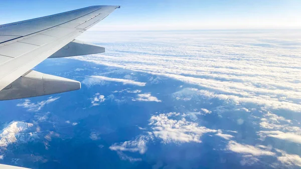 La vista desde el plano sobre el paisaje desde la ventana del plano. Ala de avión volando sobre las nubes Imagen de archivo