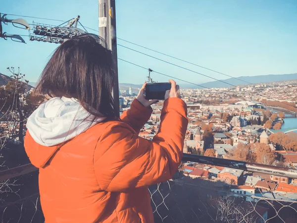 Holka v červeném saku fotí město. Krásný výhled na krajinu staré čtvrti s moderním prostorem — Stock fotografie