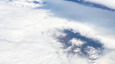 Hava görüntüsü. Mavi gökyüzünde beyaz bulutlar. Bir uçak penceresinden güzel bulutların görüntüsü.