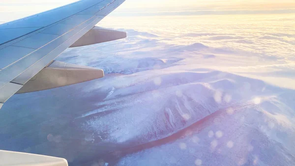 Het uitzicht vanaf het vlak op het landschap vanuit het raam van het vliegtuig. Vliegtuigvleugel die boven de wolken vliegt. — Stockfoto
