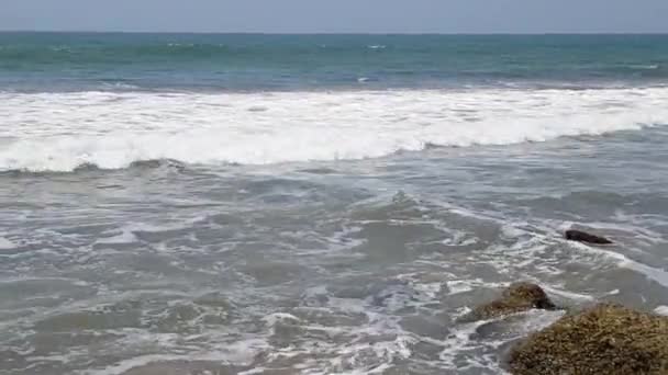 Волны разбиваются о огромные скалы на берегу — стоковое видео
