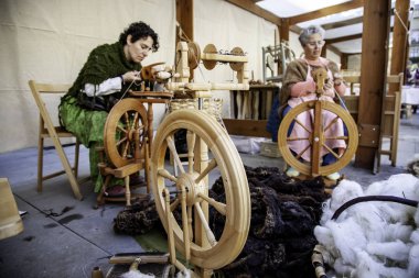  Tahta bir çarkla iplik ören kadınlar