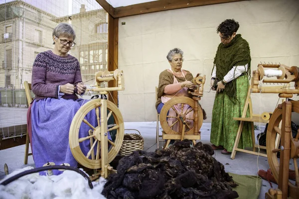 Женщины прядут нить с деревянным крутящимся колесом — стоковое фото