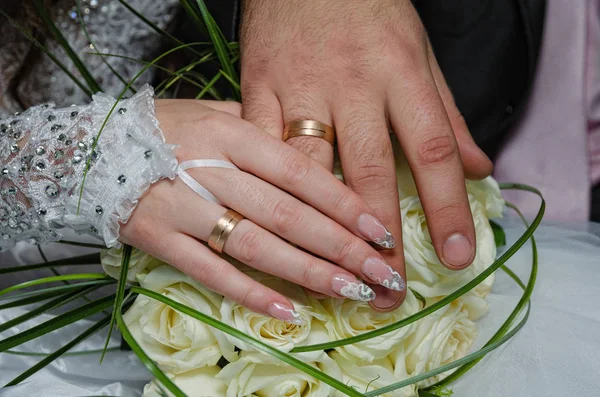 Hands of the newlyweds on a bouquet of flowers — Stock Photo, Image