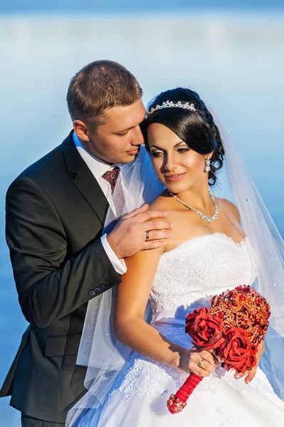 Hochzeit. Frischvermählte mit einem roten Designerstrauß aus künstlichen Blumen — Stockfoto