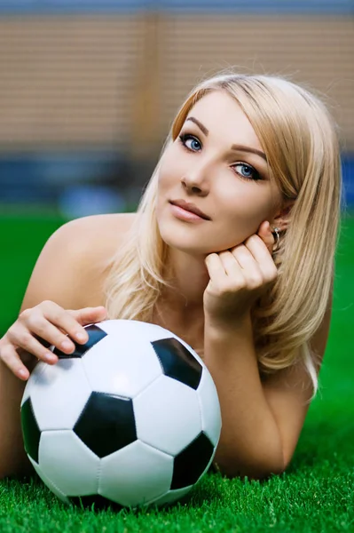 Sexy Fußball- (Fußball-) Fan. junge Blondine mit Ball posiert auf dem Feld — Stockfoto