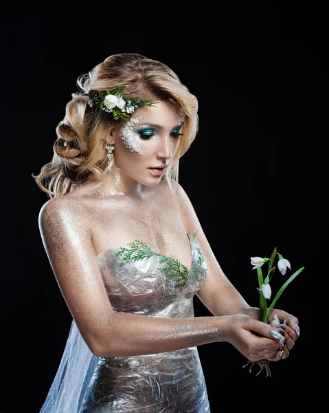 Fantasy art makeup. The snow maiden holds a newborn snowdrop in the spring — Stock Photo, Image