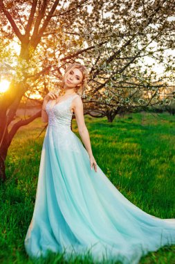 Çiçek açan ağaçlar bahçede poz uzun turkuaz elbiseli bir kız