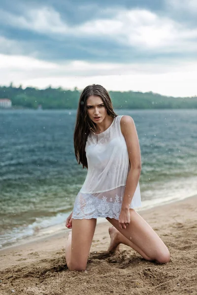 Mojado hermosa modelo posando en la playa bajo la lluvia —  Fotos de Stock