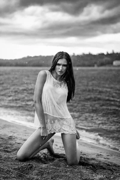 Mojado hermosa modelo posando en la playa bajo la lluvia — Foto de Stock