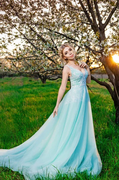 Çiçek açan ağaçlar bahçede poz uzun turkuaz elbiseli bir kız — Stok fotoğraf