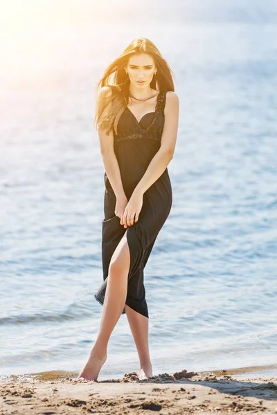 Mujer en vestido largo negro en una playa —  Fotos de Stock