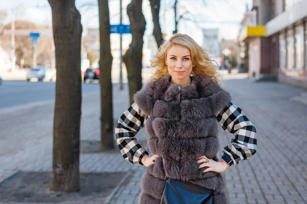 Young girl in a fur coat posing in the city — Stock Photo, Image