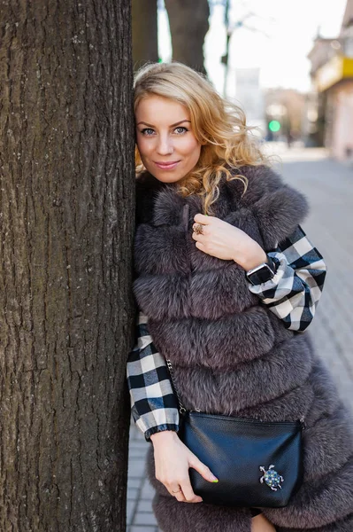 Young girl in a fur coat posing in the city — Stock Photo, Image
