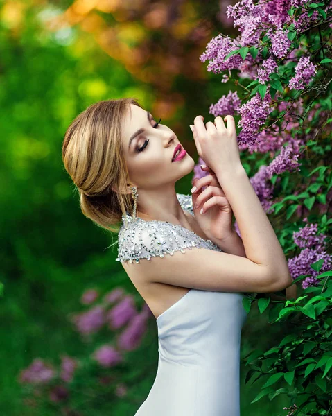 Elegante modella in un lungo abito bianco in posa nel parco — Foto Stock