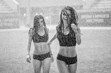 Sulama ile eğleniyor bir futbol sahasında iki sevimli ponpon kızlar