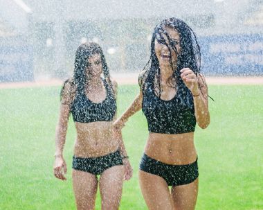 Sulama ile eğleniyor bir futbol sahasında iki sevimli ponpon kızlar