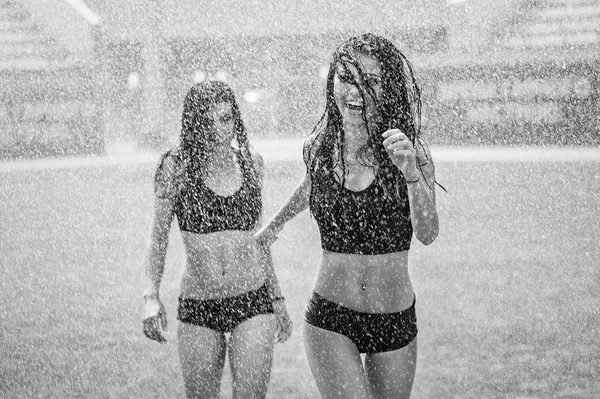 Sulama ile eğleniyor bir futbol sahasında iki sevimli ponpon kızlar