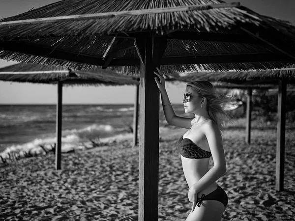 Gyönyörű lány a nyaralás a tengerparton, közel a tenger, bujkál a nap alatt egy esernyő (fekete-fehér) — Stock Fotó