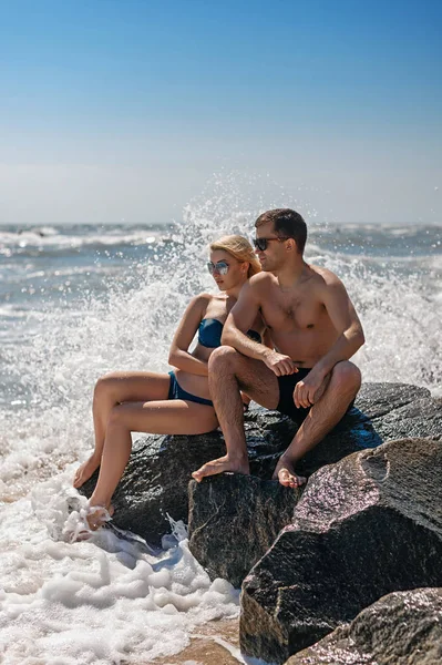 Beautiful couple posing by the sea on a stone — Stock Photo, Image