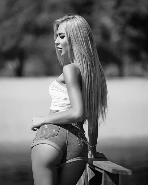 Förförisk blondin i casual sommarkläder poserar på en bro (svart och vit) — Stockfoto