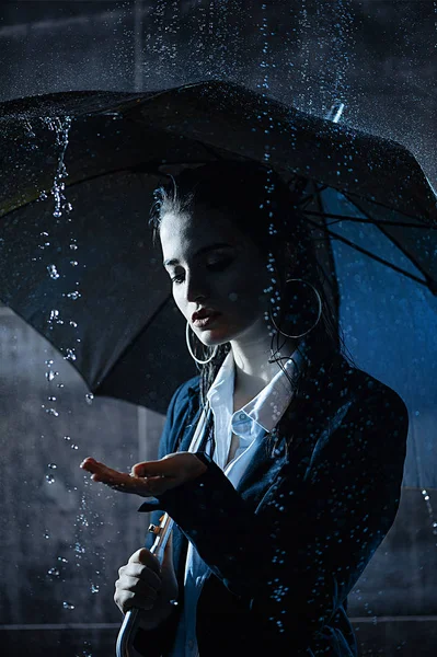 Wet brunette under the falling drops of rain in a jacket