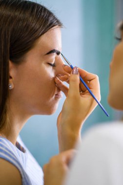 Kaş ustası, kız için kaş şeklinin modellemesini ve düzeltmesini yapıyor. Kına ya da boyalı kaş boyası.