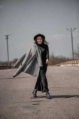 Gri paltolu çekici bir esmer yol boyunca yürüyor.