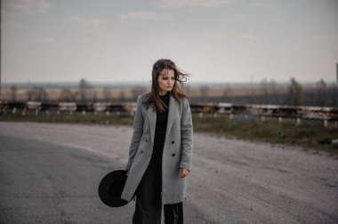 Gri paltolu çekici bir esmer yol boyunca yürüyor.