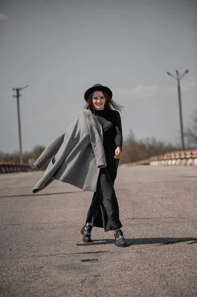 Gri paltolu çekici bir esmer yol boyunca yürüyor.