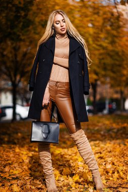 Sonbahar ceketli bir sarışın parkta yürüyor. Mevsimlik fotoğraf. Cazibe Moda