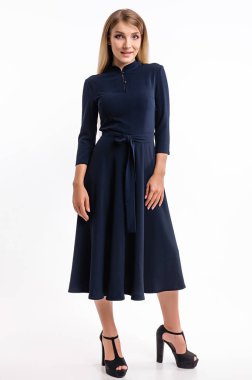 Beyaz bir duvara karşı elbise giymiş çekici bir kız.