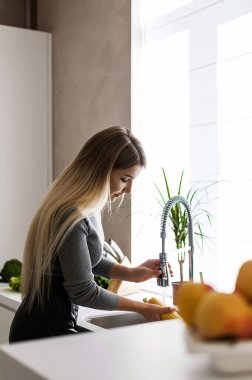 Çekici sarışın mutfakta yemek pişiriyor.